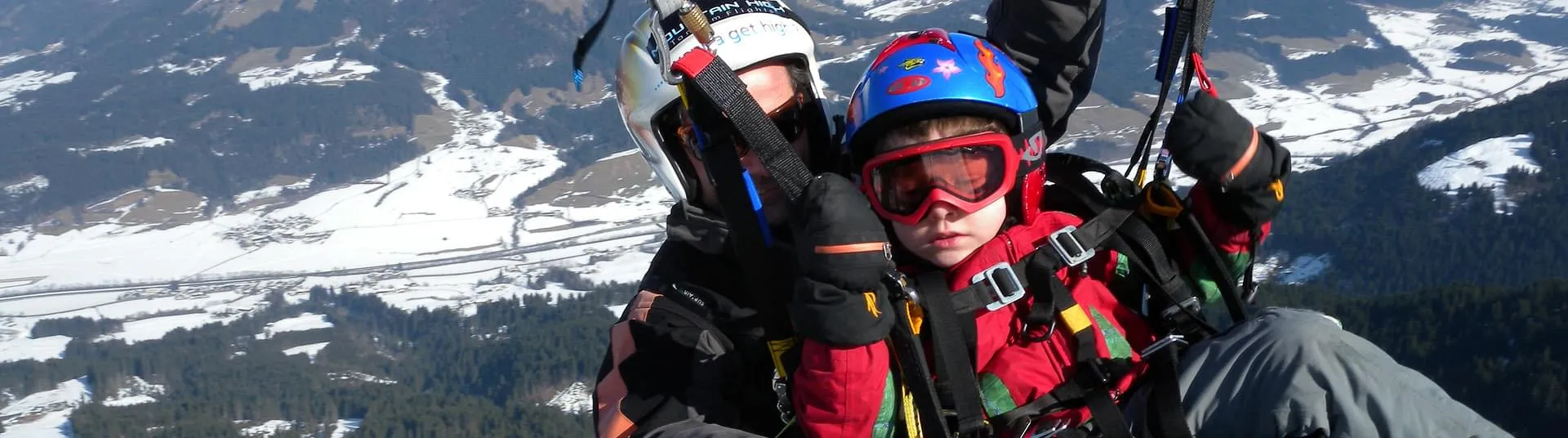 Ein mutiger Junge beim Tandem Paragleiten im Winter