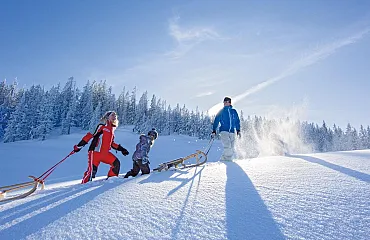 Rodelpartie in der tief verschneiten Winterlandschaft